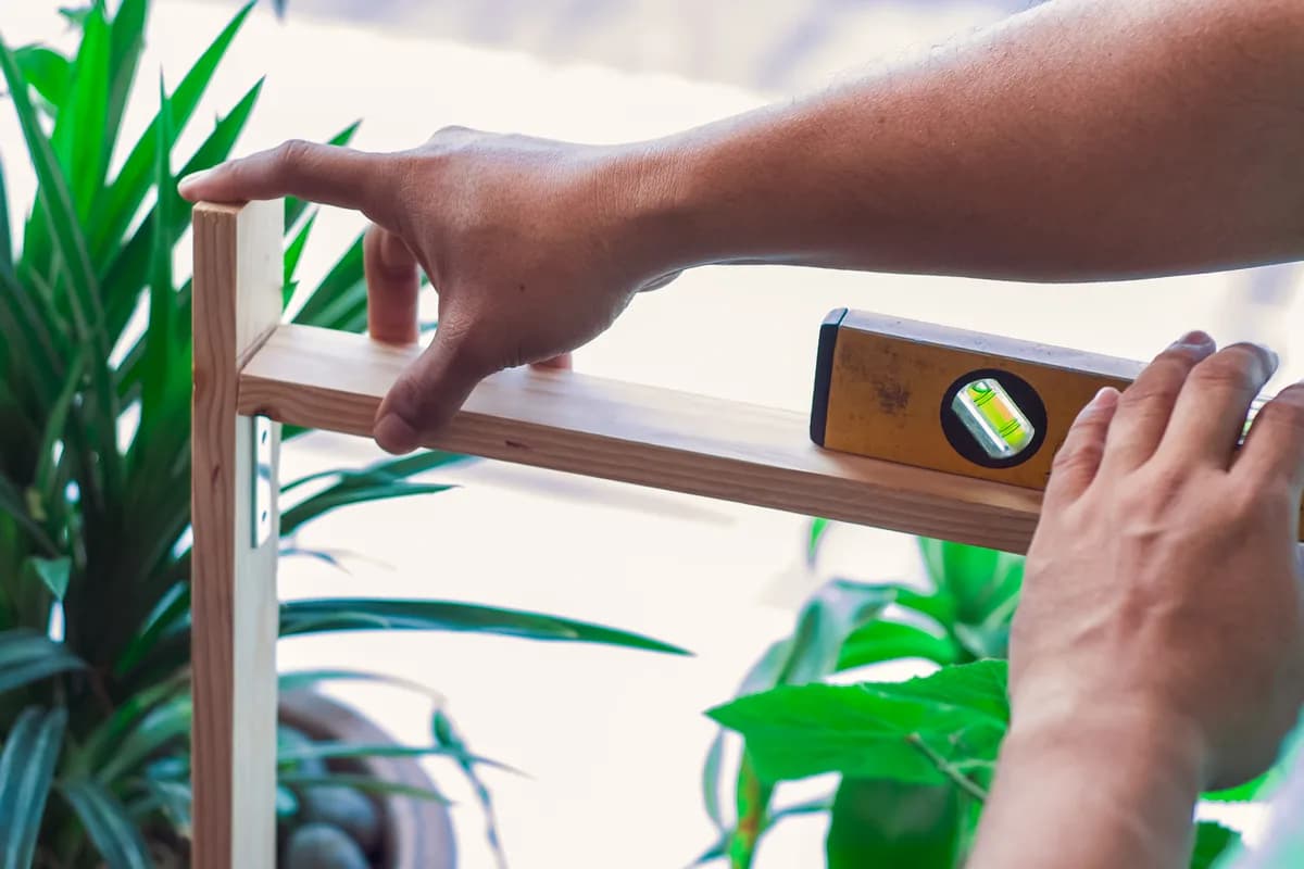 Handyman mounting a shelf with a level and drill